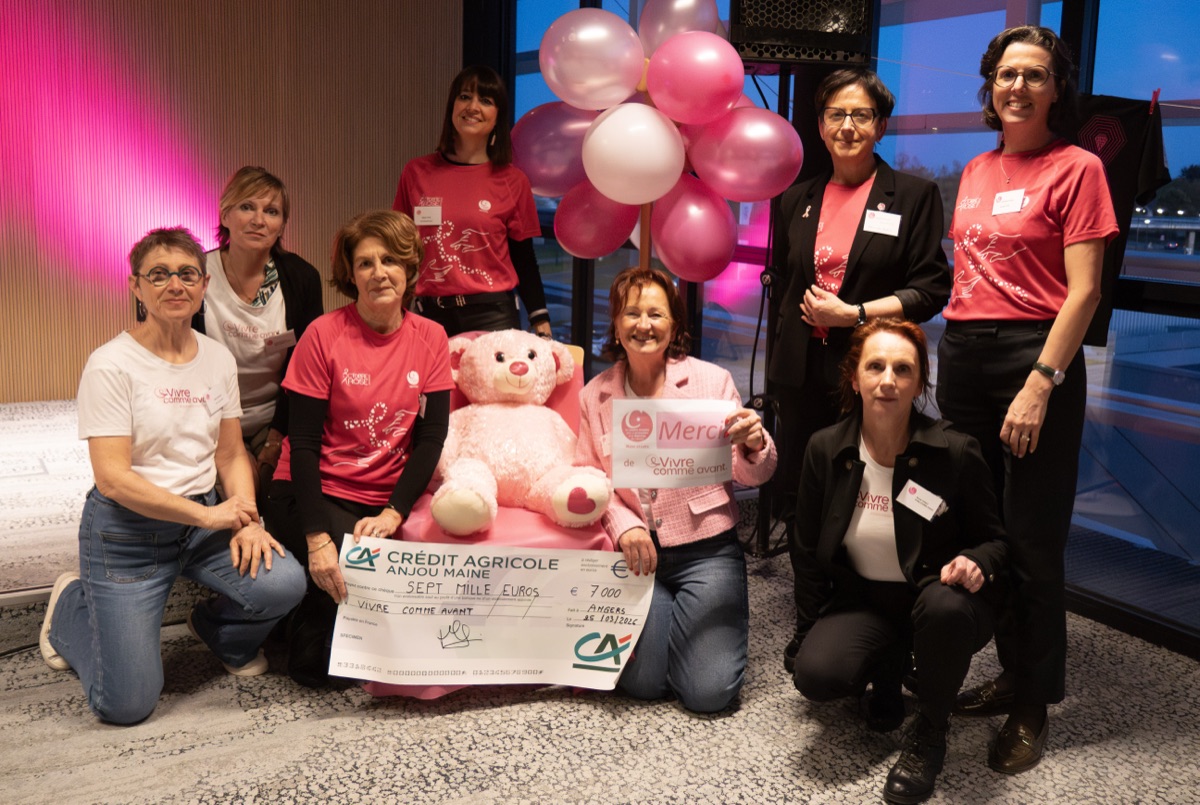 Groupe de bénévoles avec ballons roses et chèque solidaire